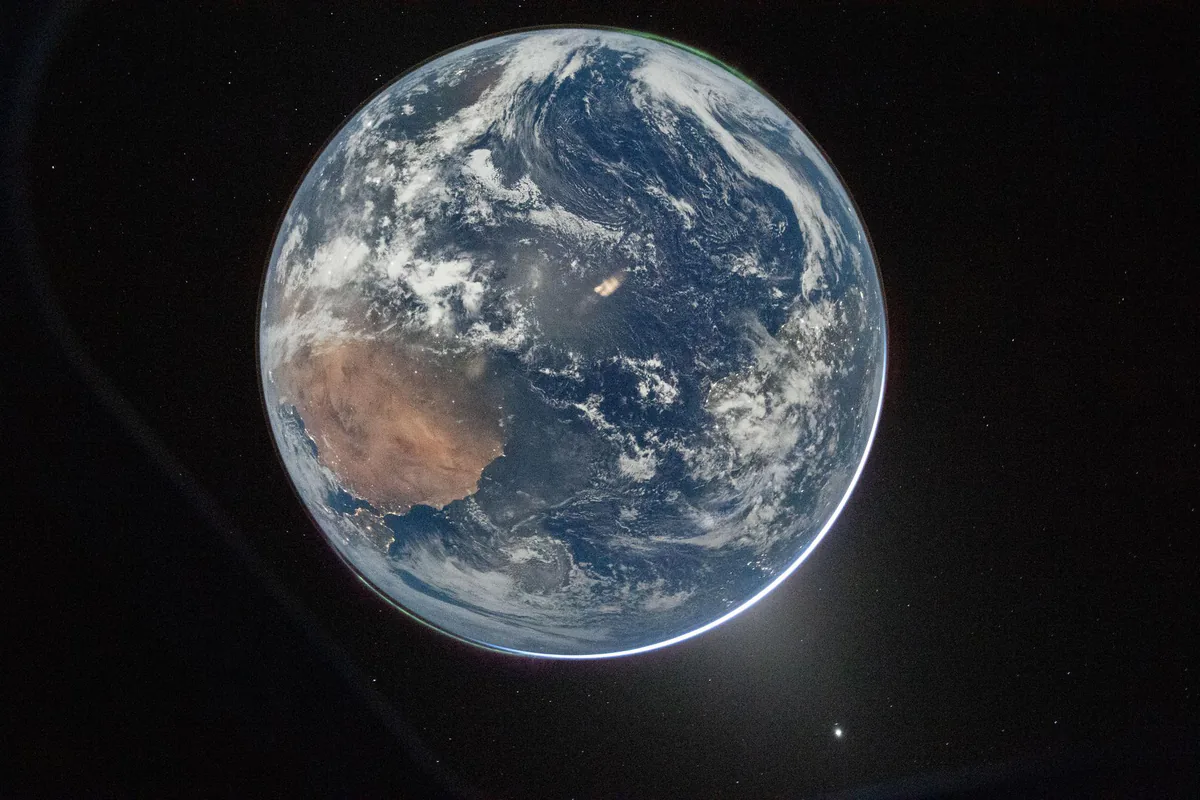 Die Erde als volle Kugel mit Afrika und weißen Wolkenbändern vor schwarzem Hintergrund